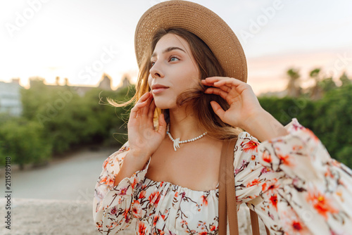 Bild auf Leinwand A woman stands on a bridge during sunset, smiling and looking thoughtful