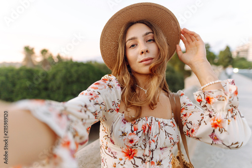 Bild auf Leinwand A woman stands on a bridge during sunset, smiling and looking thoughtful