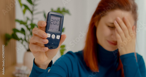 Foto A woman looks shocked as she shows her glucometer reading of 200 mg dL