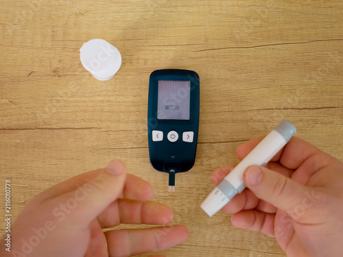 A man prepares to check his blood sugar level. He inserts a test strip into a glucometer to measure glucose. This is important for managing diabetes.
