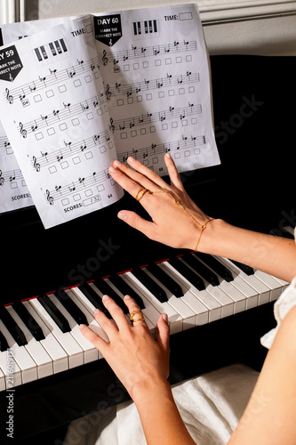 pianist female hands wearing jewelry playing piano and music notes