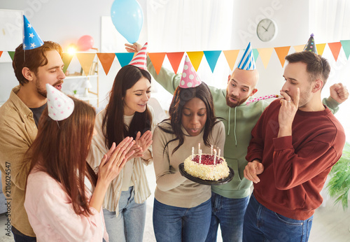 Quadro su tela Happy birthday cake, multiethnic friends in funny caps, company congratulate bla