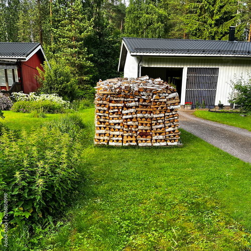 Woodpile Stacked of Birch Firewood on a Green Lawn next to Residential Houses in Porvoo, Finland.