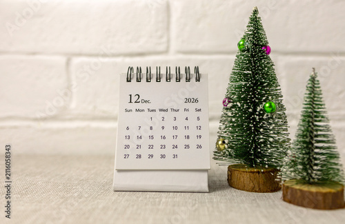 Desk calendar for December 2026 and a Christmas tree on the table.