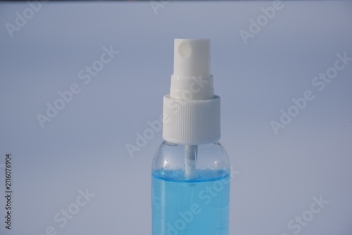 Close up of white spray pump nozzle on clear alcohol sanitizer bottle with blue liquid