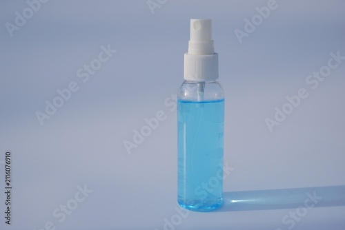 Transparent spray bottle filled with blue alcohol hand sanitizer spray on plain background, Healthcare concept