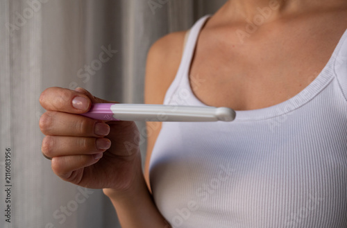 Close-up of woman holding home pregnancy test, fertility, early pregnancy and reproductive health concept