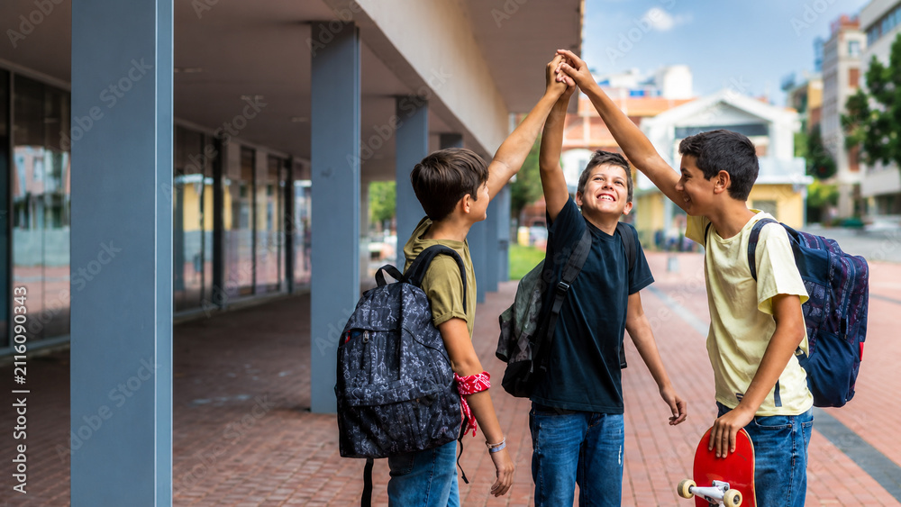 Obraz premium Happy school friends celebrating friendship with high five after classes in urban campus