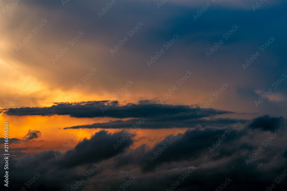 Fototapeta premium Dramatic cumulonimbus storm clouds illuminated by golden sunset light above dark rain clouds creating an extreme weather sky, atmospheric landscape and climate change background with copy space.