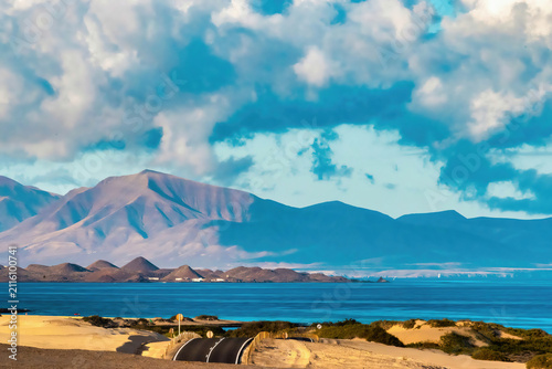 Photography Road by the beach with mountains and clouds in the background during daytime