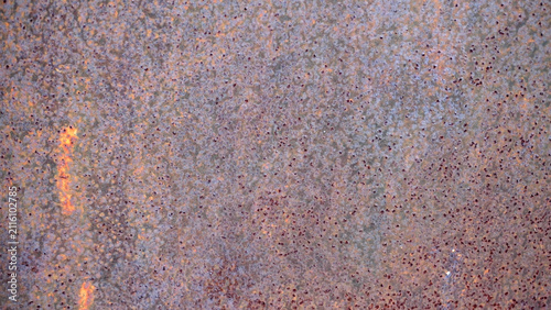 Foto Grungy rusted metal surface texture with speckled corrosion and warm glow