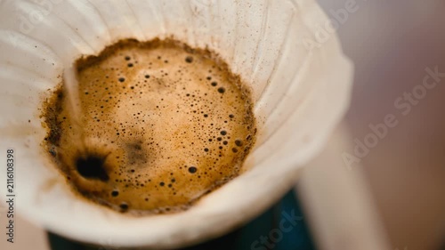 Pour over coffee brewing top view, drip filter coffee blooming with bubbles macro shot, water pouring over ground coffee, specialty coffee extraction process