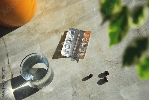 Empty pill blister, capsules, and glass of water on stone surface