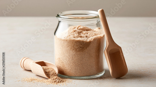 psyllium. Psyllium powder in glass jar with wooden scoop, diagonal arrangement on workspace surface, dietary fiber supplement and natural wellness concept, STEM education sheets.