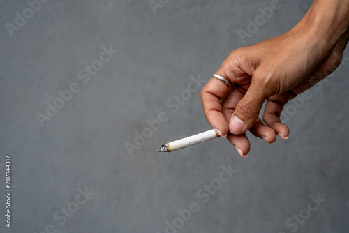 Woman's hand holding a cigarette, and the cigarette is burning.