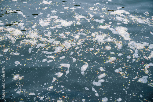 8K photos of marine water pollution with floating plastic debris and foam on sea surface.