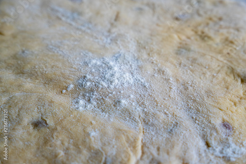 Foto White wheat flour light dusting sits on top of rolled raw yeast pastry dough, showing detailed surface texture during homemade baking preparation