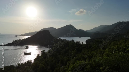 Sunlit tropical bay with lush mountains at golden hour