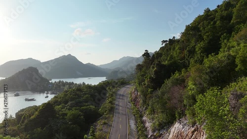 Scenic coastal road winding through lush tropical hills beside the ocean