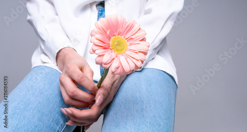 Obraz na plátně Young woman with pink flower on bright studio background, ideal for beauty, styl