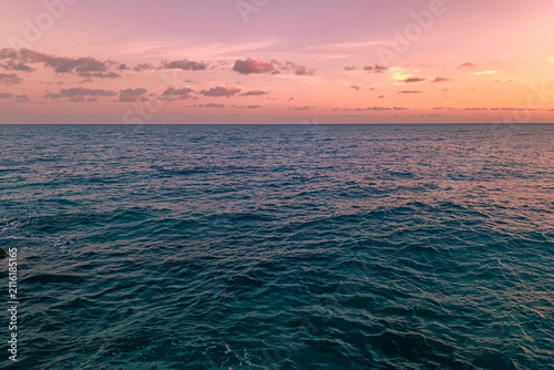 Cuadro en lienzo A seascape with an endless blue ocean under a delicate pink-orange sky at sunset or sunrise