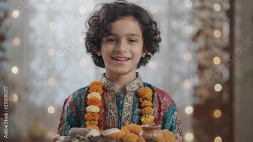 Smiling Indian boy in traditional attire holding a festival thali
