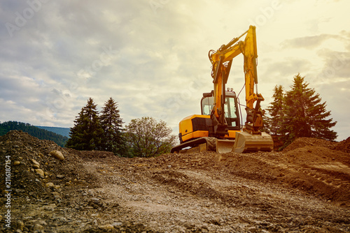 Yellow excavator on a construction site digging dirt and moving earth during development