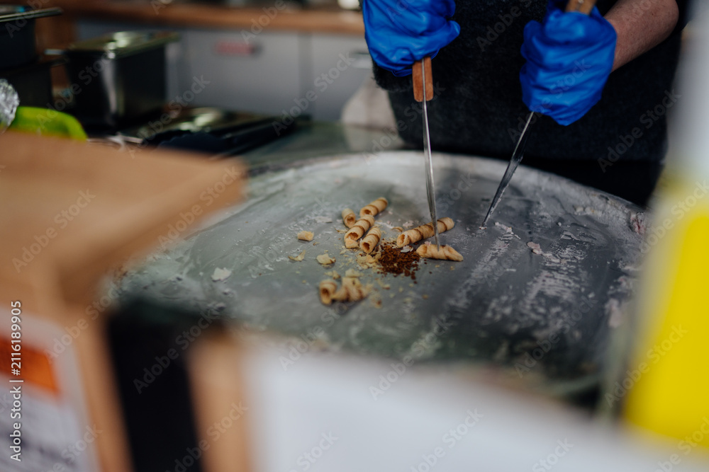 Fototapeta premium Dessert vendor arranging freshly made rolled ice cream curls on a freezing metal plate