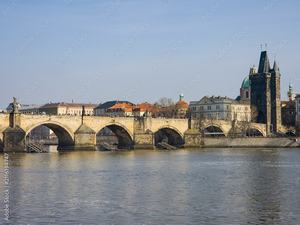 Fototapeta premium View of an old stone arch bridge over a river in Prague Praha European city seen from the below on the water with architectural beauty