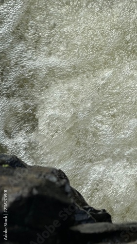 Frothing Whitewater Rapid Flowing Past Wet Rock