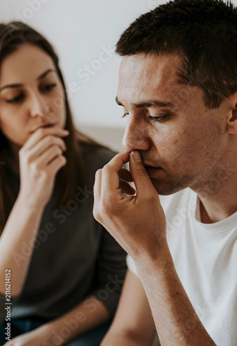 Man pinching his nose with a woman in the background expressing discomfort or a smell relationship communication, this scene concepts of unpleasantness disagreement or a difficult conversation