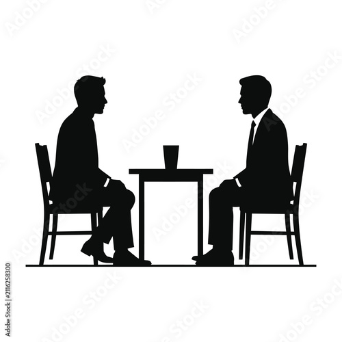 Two businessmen in suits sitting at small table facing each other in meeting
