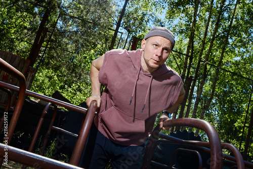 Caucasian young adult man exercising on parallel bars in outdoor fitness park, building upper body strength and endurance. Useful for sports training, wellness, active lifestyle marketing