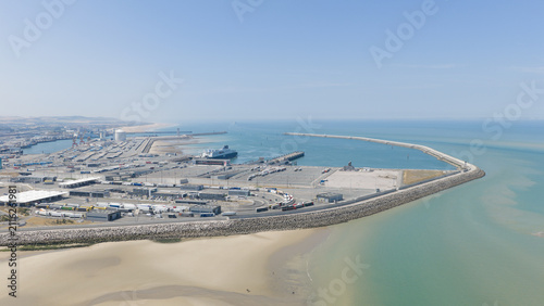 Calais, France - 09 July 2026: Aerial view of the Port of Calais ferry entrance with cargo trucks, terminal facilities, and breakwater extending into the English Channel.