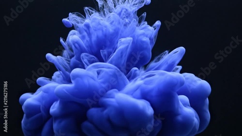 Blue ink swirl diffusing in black water background.
