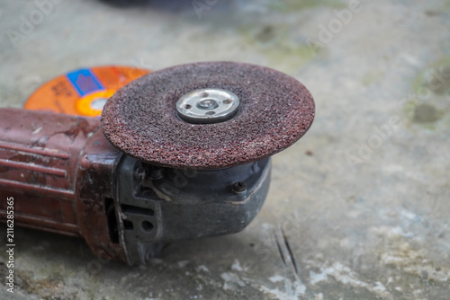 Close-up of an angle grinder with a worn cutting disc on a textured surface.