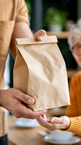 Delivery support for elderly, courier hands paper bag to senior, volunteer care service, compassionate assistance, community help, warm human interaction, social support concept.