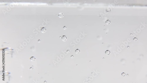 Clear water fills the frame in close-up as small bubbles float and drift slowly upward and sideways across the glass surface, creating a calm and satisfying ASMR scene throughout.