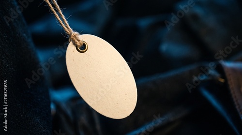 Blank oval tag hanging by twine against a dark textured background