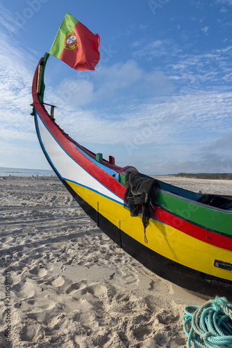 Traditional Arte Xavega fishing boat on an Ovar beach with a Portuguese flag