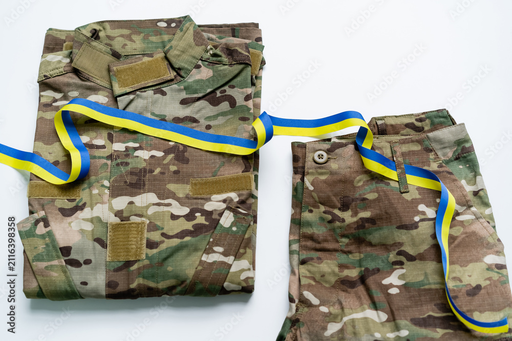 Obraz premium Camouflaged military uniform shown with a blue and yellow ribbon of national pride.