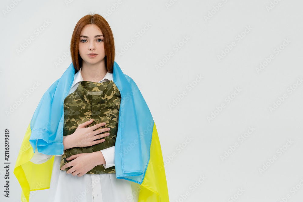 Obraz premium A young Ukrainian woman wraps herself in the flag, symbolizing her strength on Independence Day.