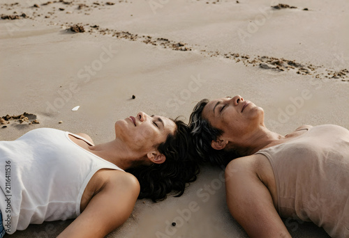 Two women lying on a sandy ...