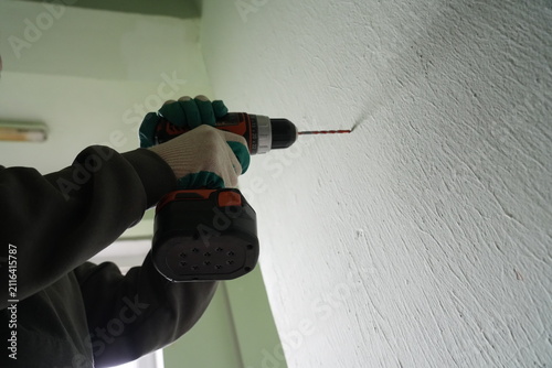 Low angle of worker drilling plaster wall with power tool