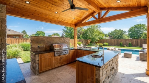 Outdoor kitchen with stone walls, wood ceiling, and patio furniture.