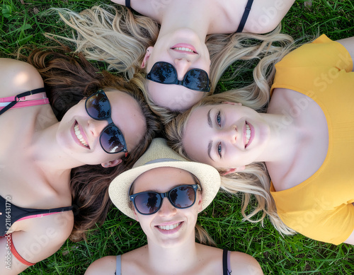 Top View Close Up of Happy Young Women Lying in Circle on Lawn Under Sun