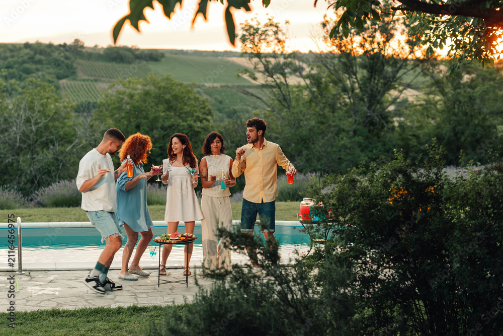 Obraz premium Friends celebrating poolside, enjoying summer cocktails and lively conversation during a sunset social event
