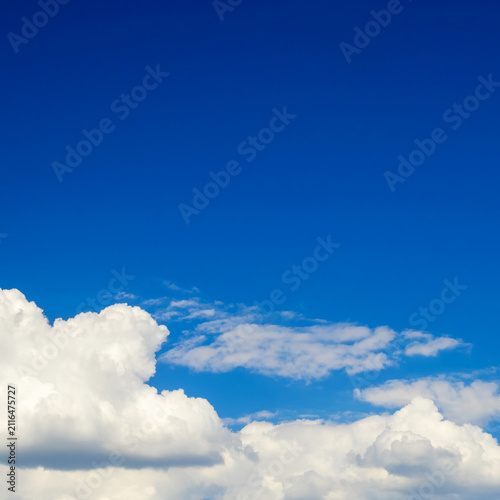 fluffy white cumulus clouds at the bottom of bright blue sky