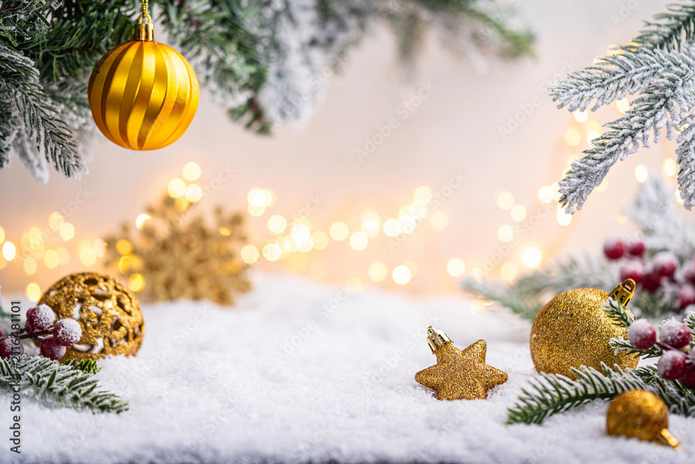 Obraz premium Glittering gold ornaments and snowflakes rest on snowy ground with frosted pine branches and soft glowing lights. Winter Christmas Holiday Decoration Background