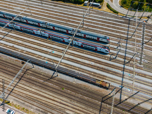 Aerial view of Daniken train station with multiple parallel tracks, modern passenger trains, and a freight train in Daniken, Solothurn, Switzerland.